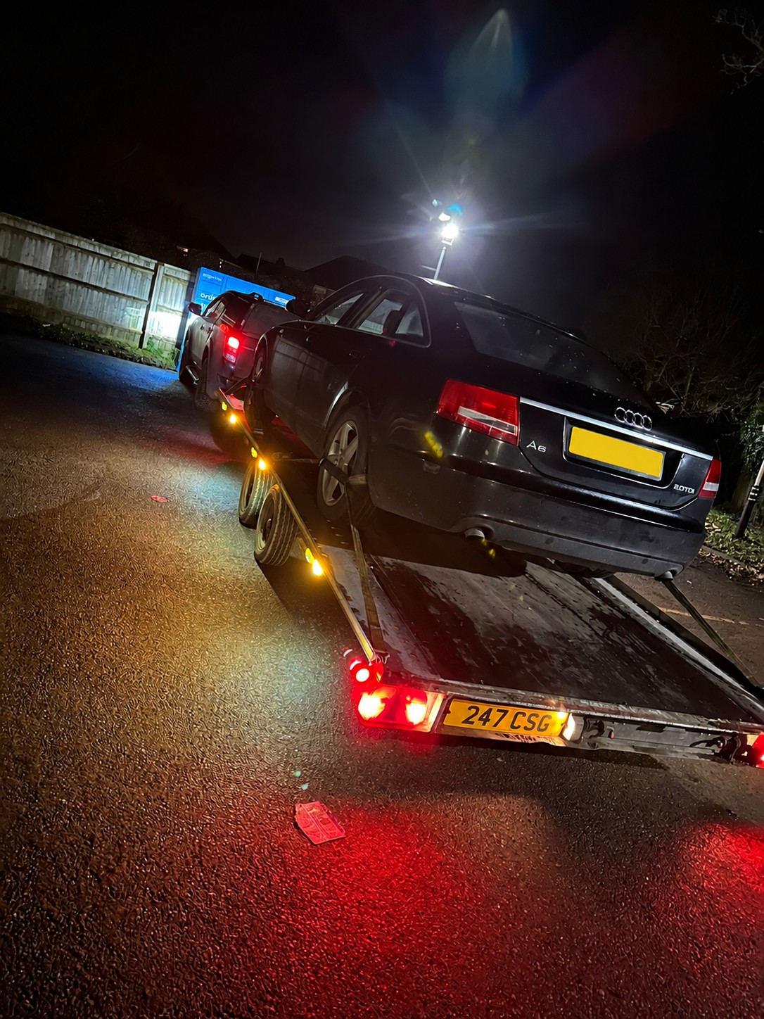 Black Audi secured on a CSG recovery trailer at night