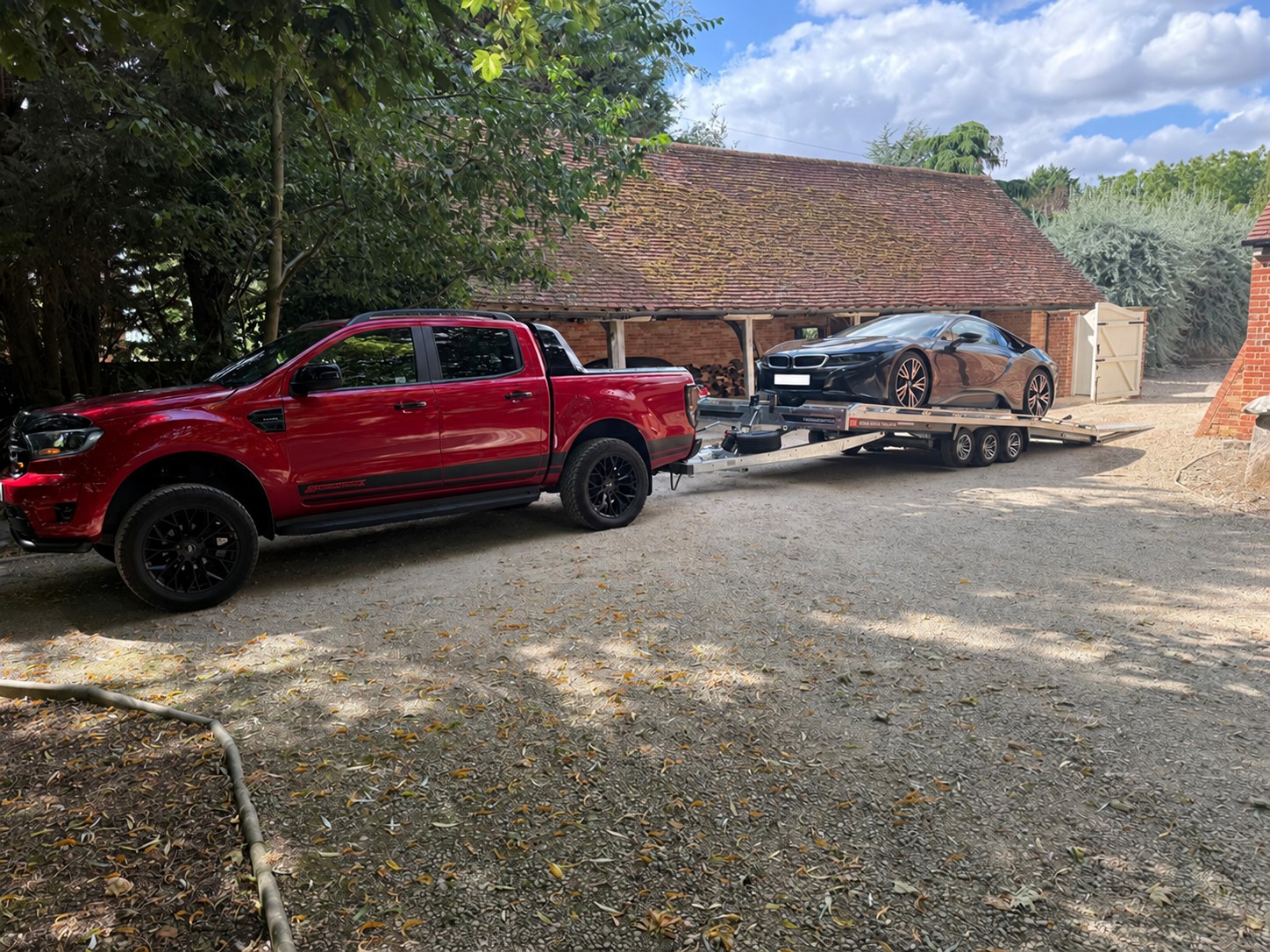 Red CSG pickup transporting a BMW i8 on a vehicle trailer