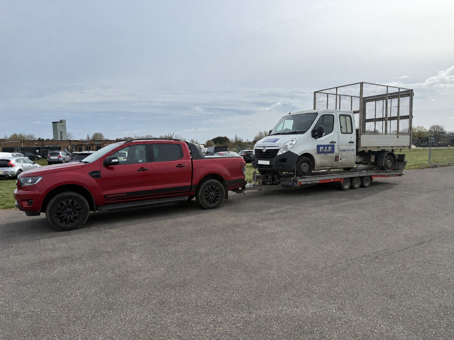 Red CSG pickup transporting a white cage-body commercial van