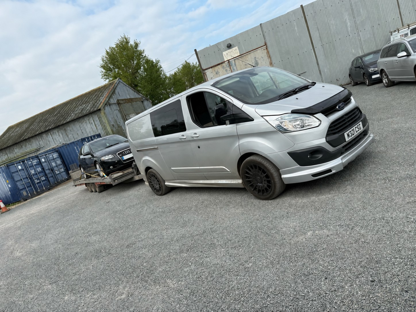Silver CSG van towing a black Audi on a vehicle trailer