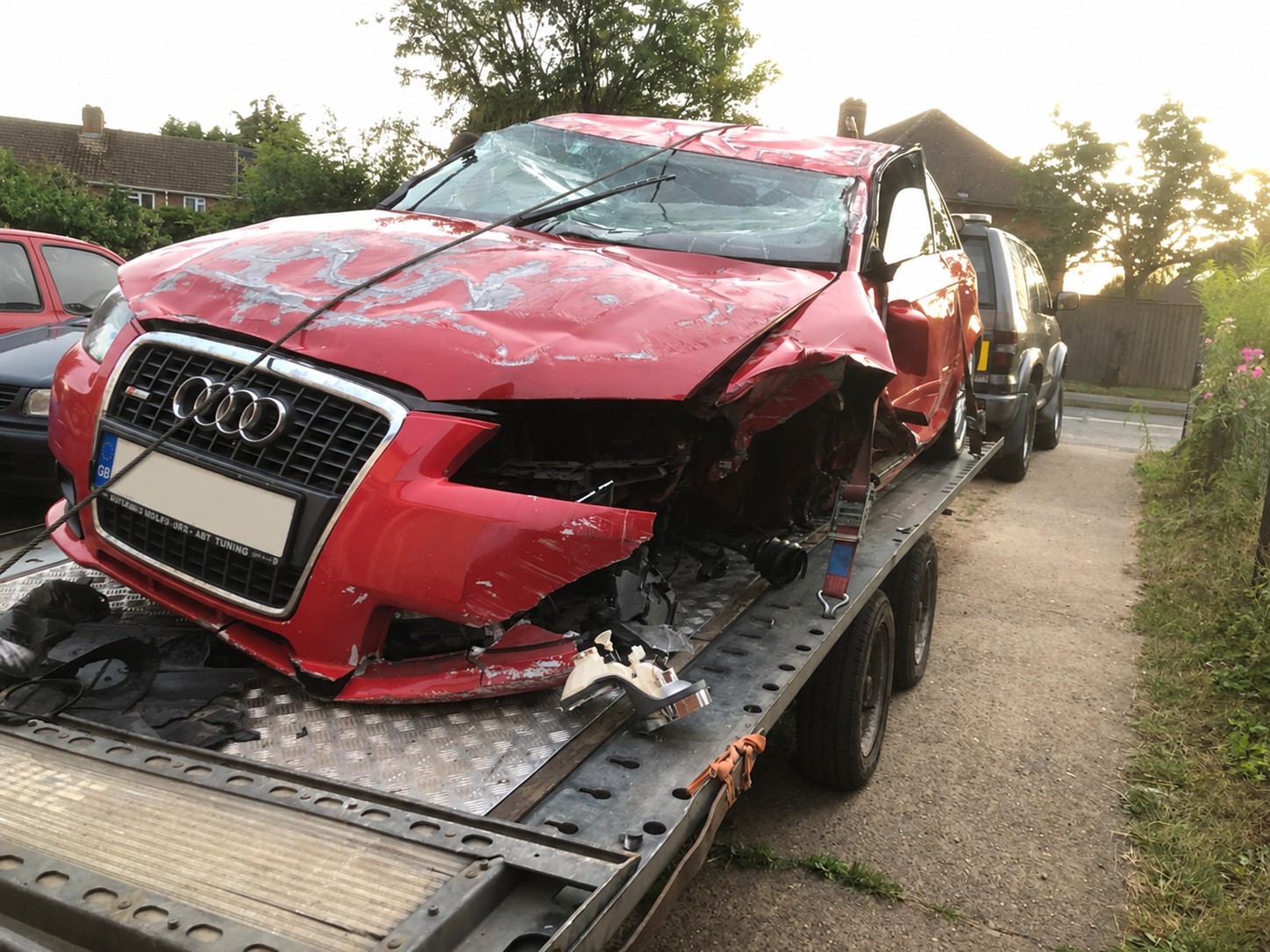 Damaged red Audi secured on a recovery trailer