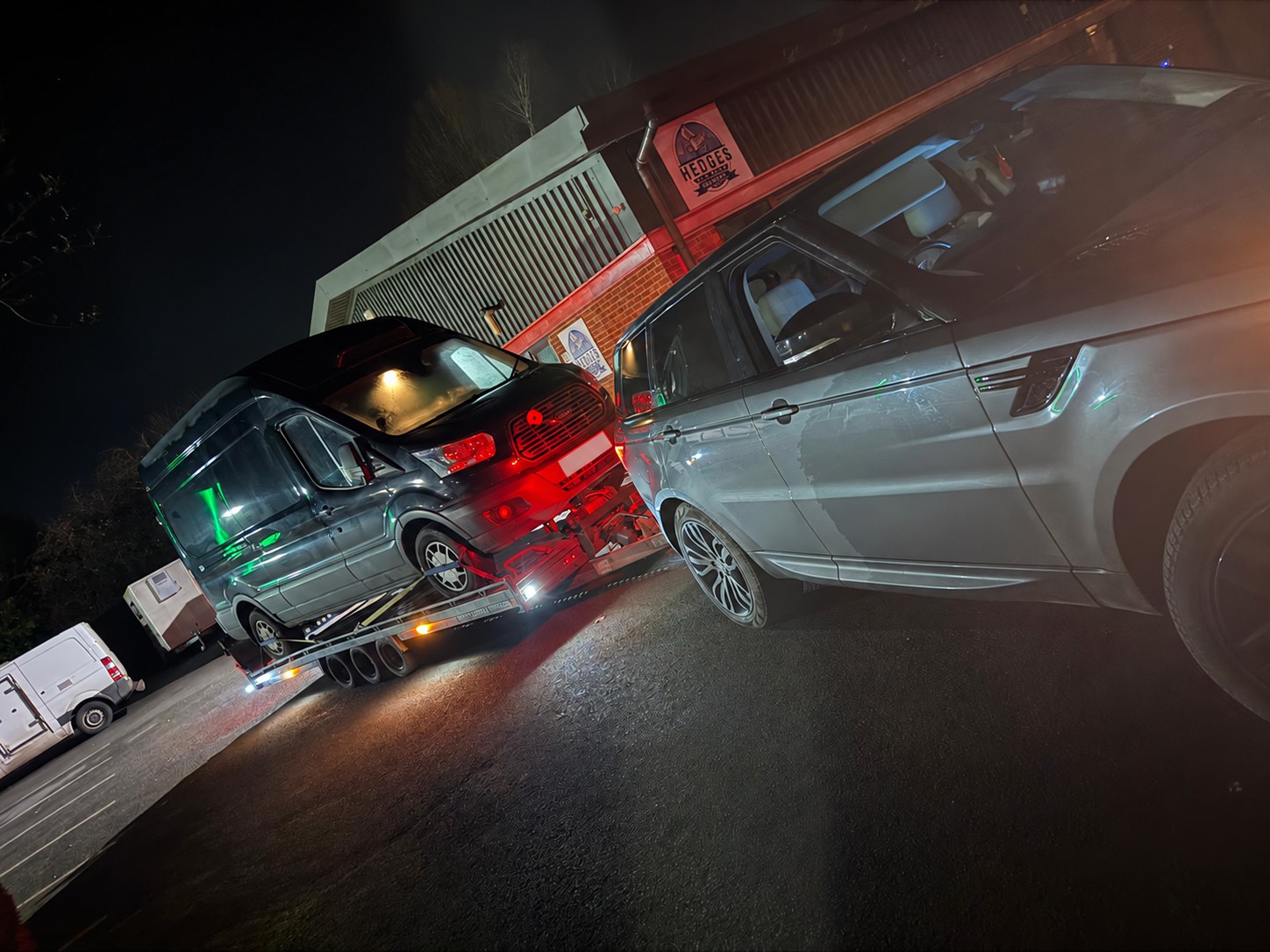 Dark Ford camper van carried on a recovery trailer at night