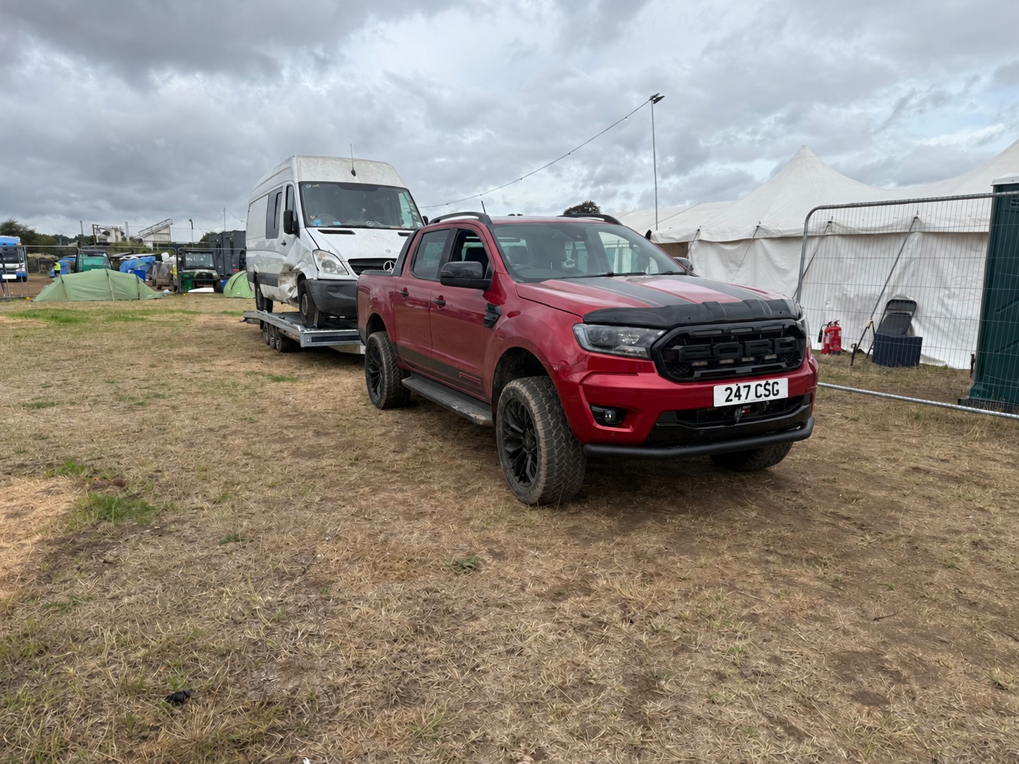 Red CSG pickup recovering a white Mercedes van at an outdoor event