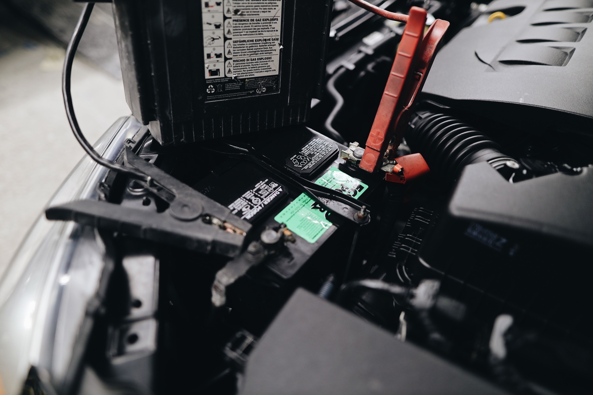 Portable jump-start booster with red and black clamps connected to a vehicle battery