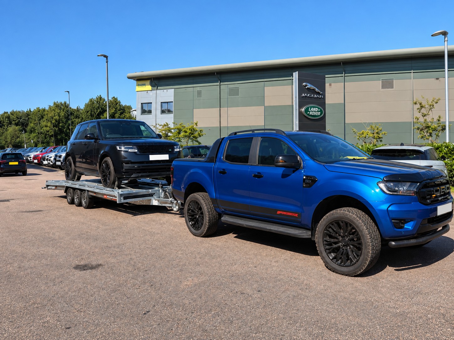 Blue pickup transporting a black Range Rover from a dealership