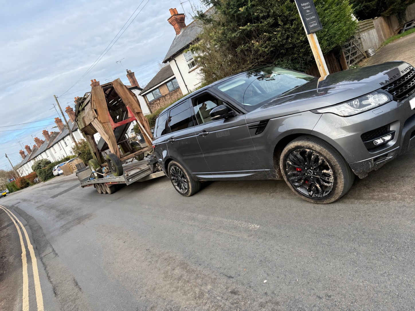 Range Rover towing a tall wooden structure on a transport trailer