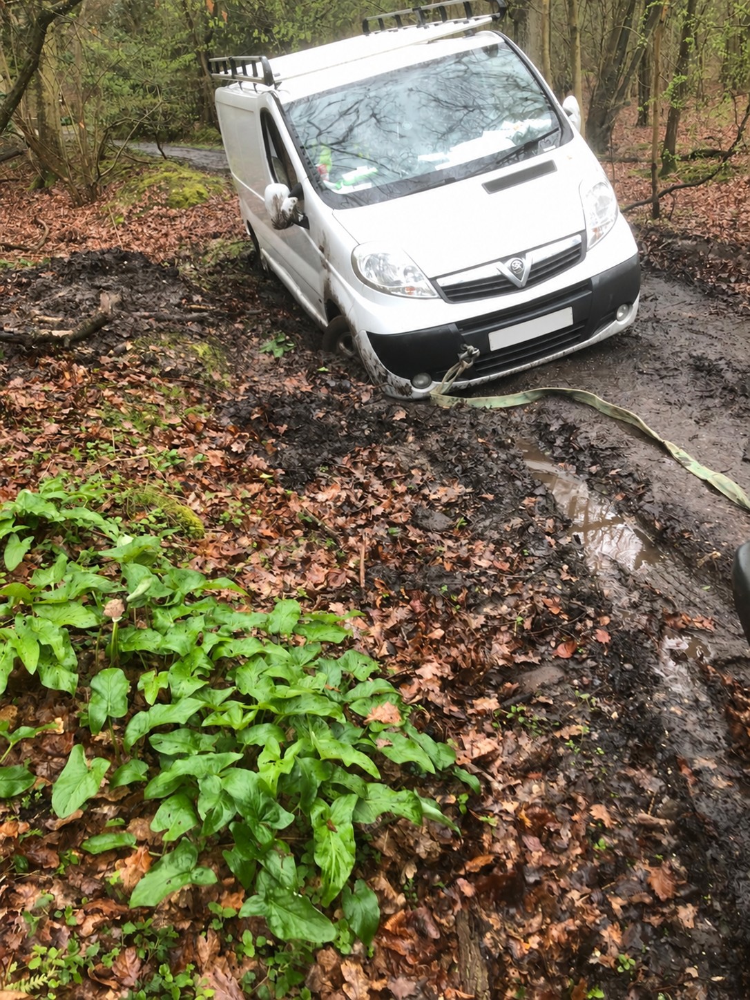 White Vauxhall van stuck in woodland mud with a recovery strap attached