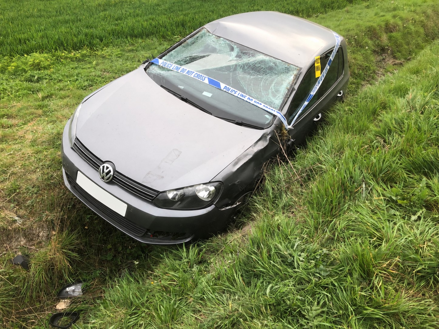 Front view of a damaged grey Volkswagen Golf in a grassy ditch